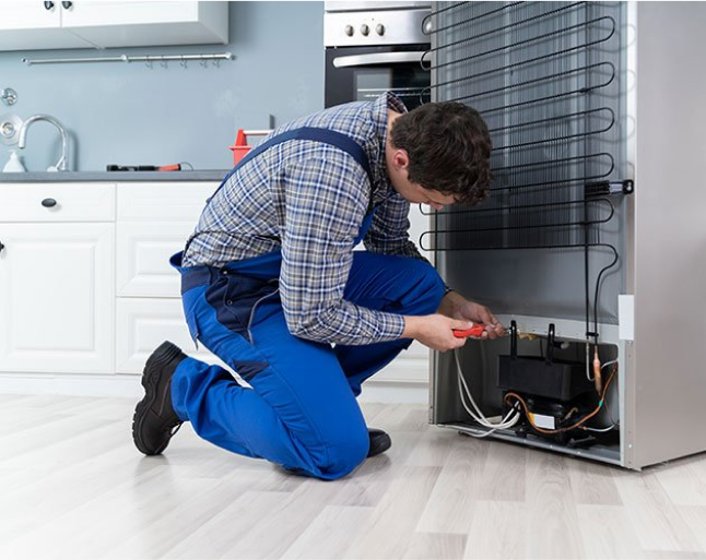 Technician repairing a refrigerator in a kitchen.